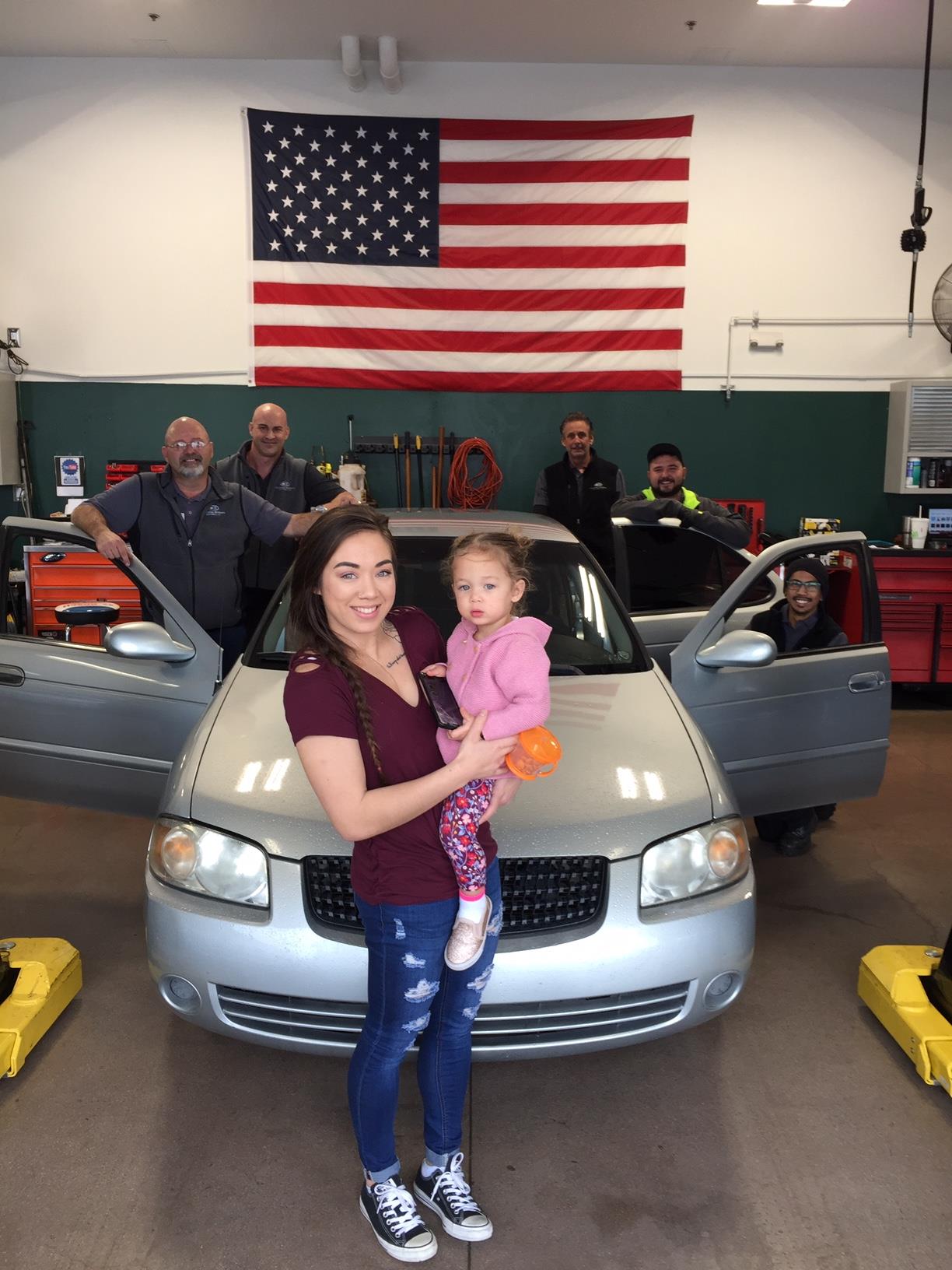 people in front of car in christian brothers automotive shop