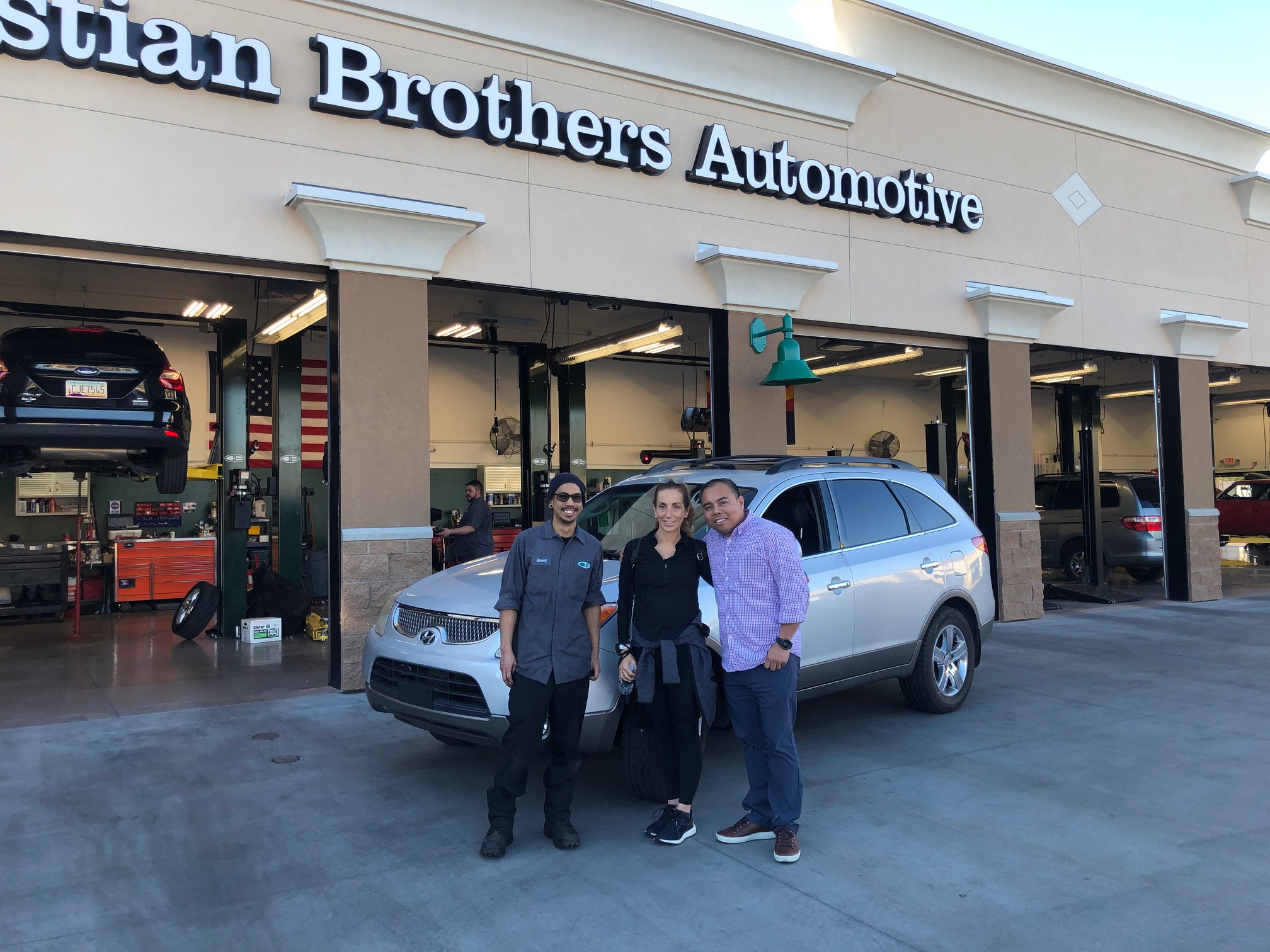 people in front of car in front of christian brothers automotive shop