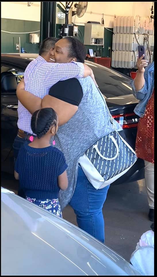 customer hugging christian brothers automotive employee