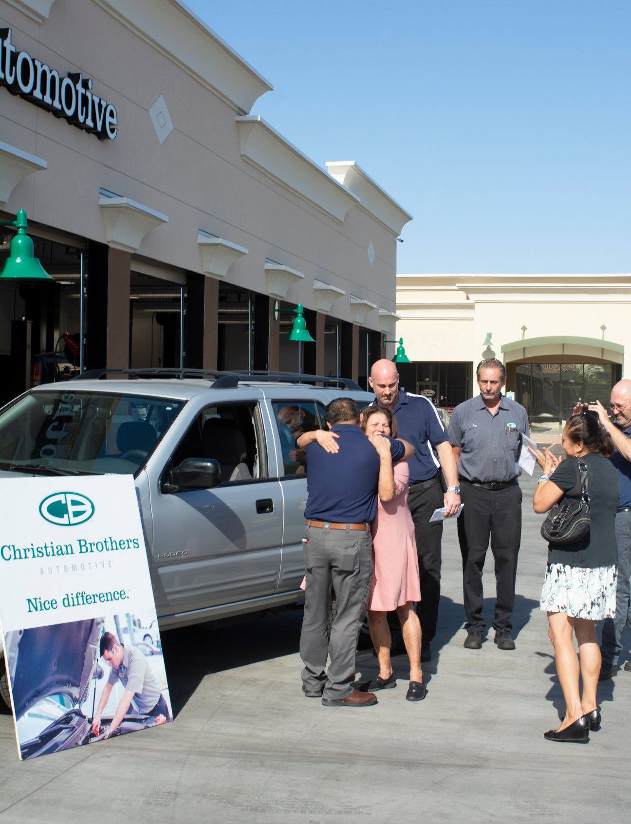 people in front of car in front of christian brothers automotive shop